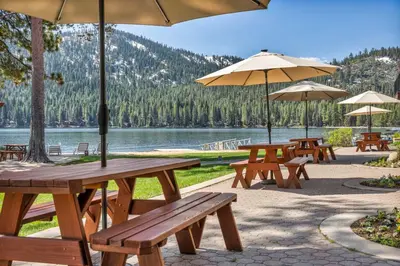 a group of picnic tables with umbrellas and a lake at Charming Studio Deluxe w/kitchen #215 at Donner Lake Village in Truckee