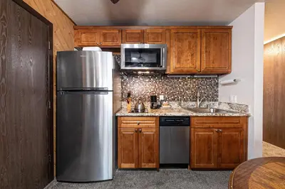 a kitchen with wooden cabinets and a stainless steel refrigerator at Cozy Studio w/Kitchenette Easily Accessible #113 at Donner Lake Village in Truckee