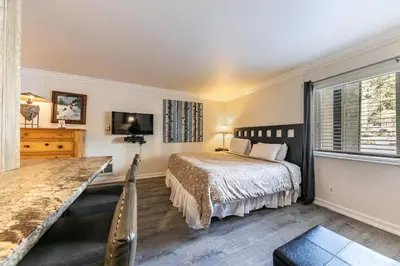 a bedroom with a bed and a dresser and a window at Charming Studio Deluxe w/Full Kitchen #115 at Donner Lake Village in Truckee