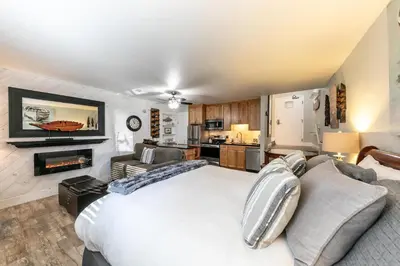 a bedroom with a white bed and a kitchen at Partial Lake View Stunning Deluxe King Studio #125 at Donner Lake Village in Truckee