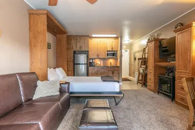 a living room with a bed and a leather couch at Cozy Studio 1st Floor #132 at Donner Lake Village in Truckee