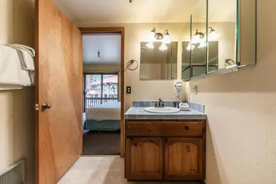 a bathroom with a sink and a mirror and a bed at Comfortable Townhouse w/Lake View #154 at Donner Lake Village in Truckee