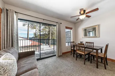 a living room with a couch and a dining room table with a window at Beautiful Studio w/ Lake View #243 at Donner Lake Village in Truckee