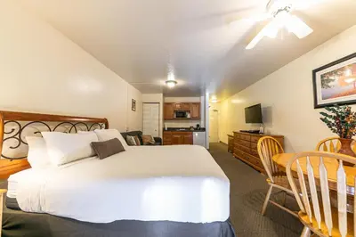 a bedroom with a large white bed and a kitchen at Cozy Studio #226 at Donner Lake Village in Truckee