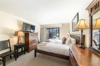 a bedroom with a bed and a dresser and a desk at Spacious 1BR Condo w/Partial Lake View #222 at Donner Lake Village in Truckee