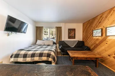 a hotel room with a bed and a couch and a tv at Cozy Studio w/Kitchen #112 at Donner Lake Village in Truckee