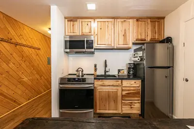a kitchen with wooden cabinets and a stainless steel refrigerator at Cozy Studio w/Kitchen #112 at Donner Lake Village in Truckee