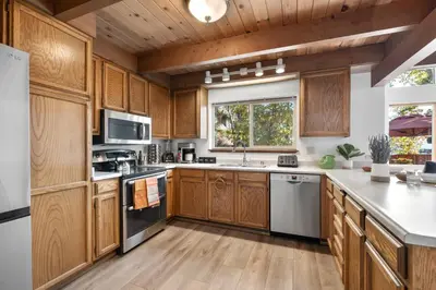 a large kitchen with wooden cabinets and a window at Waves End Lakefront - 3BR Tahoe Vista w Private Sandy Beach, Walk to Town! in Tahoe Vista