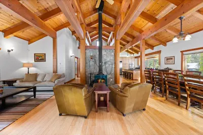 a living room with a fireplace and a table at Copperleaf Lodge by Tahoe Getaways - Updated 5BR Alpine Meadows Chalet w Private Hot Tub, Ski Shuttle! in Alpine Meadows