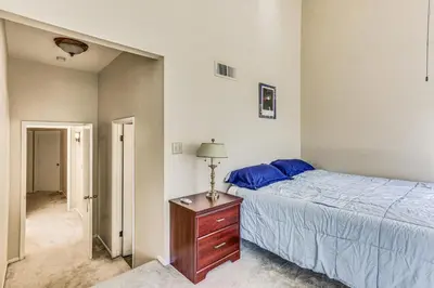 a bedroom with a bed and a dresser with a lamp at Spacious Downtown Fresno Townhome Walk to UCSF in Fresno
