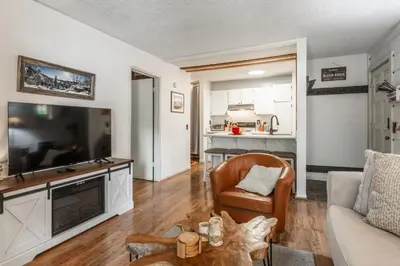 a living room with a large television and a couch at Cozy Cabin-Style Condo in Central Location in Mammoth Lakes
