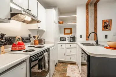 a kitchen with white cabinets and a stove top oven at Cozy Cabin-Style Condo in Central Location in Mammoth Lakes