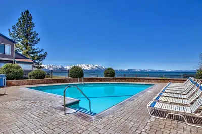 a swimming pool with lounge chairs next to a house at Lakeland Village 620 - Beachfront Bliss in South Lake Tahoe