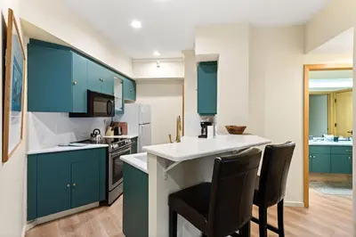 a kitchen with blue cabinets and a counter with two chairs at Palisades Tahoe Lodge Rentals One Bedroom #120 in Olympic Valley