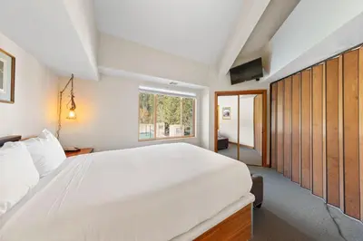 a bedroom with a large white bed and a window at Palisades Tahoe Lodge Rentals Premium One Bedroom #321 in Olympic Valley