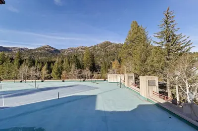 a tennis court with trees and mountains in the background at Palisades Tahoe Lodge Rentals Premium One Bedroom #321 in Olympic Valley