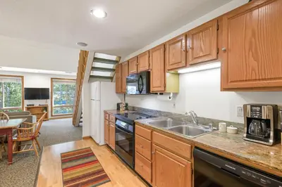 a kitchen with wooden cabinets and a sink at Palisades Tahoe Lodge Rentals Studio Loft #306 in Olympic Valley