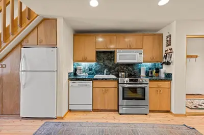 a kitchen with white appliances and wooden cabinets at Palisades Tahoe Lodge Rentals Studio Loft #315 in Olympic Valley