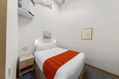 a small bedroom with a bed with an orange blanket at Palisades Tahoe Lodge Rentals Studio Loft #317 in Olympic Valley