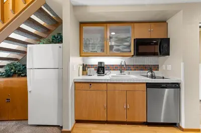 a kitchen with wooden cabinets and a white refrigerator at Palisades Tahoe Lodge Rentals Studio Loft #331 in Olympic Valley