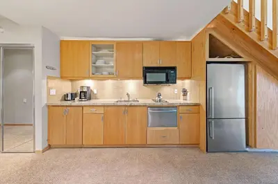 a kitchen with wooden cabinets and a stainless steel refrigerator at Palisades Tahoe Lodge Rentals Studio Loft #349 in Olympic Valley