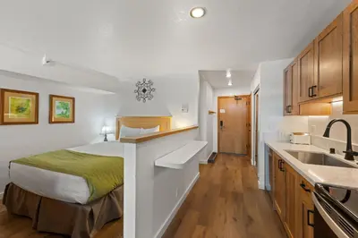 a bedroom with a bed and a kitchen with a sink at Palisades Tahoe Lodge Rentals Studio Loft #329 in Olympic Valley