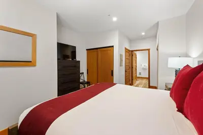 a bedroom with a large white bed with red pillows at Palisades Tahoe Lodge Rentals Premium Two Bedroom #700 in Olympic Valley