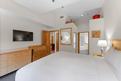 a bedroom with a white bed and a television at Palisades Tahoe Lodge Rentals Two Bedroom #521 in Olympic Valley