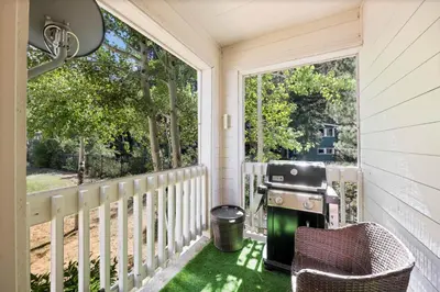a screened in porch with a grill and a chair at Palisades Tahoe Lodge Rentals Two Bedroom #512 in Olympic Valley