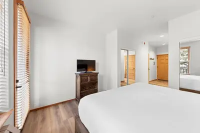 a bedroom with a white bed and a television at Palisades Tahoe Lodge Rentals Two Bedroom #705 in Olympic Valley