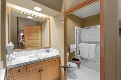 a bathroom with a sink and a toilet and a mirror at Palisades Tahoe Lodge Rentals Two Bedroom #804 in Olympic Valley
