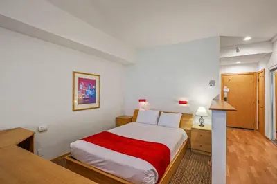a bedroom with a large bed with a red blanket at Palisades Tahoe Lodge Rentals Studio #104 in Olympic Valley