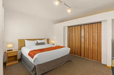 a bedroom with a large bed and a wooden closet at Palisades Tahoe Lodge Rentals Studio #144 in Olympic Valley