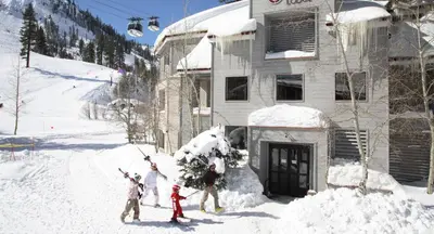 a group of people standing in the snow in front of a house at Palisades Tahoe Lodge Rentals Studio #113 in Olympic Valley