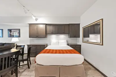 a bedroom with a bed and a desk and a kitchen at Palisades Tahoe Lodge Rentals Studio #117 in Olympic Valley