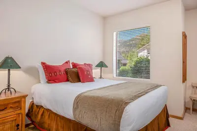 a bedroom with a bed with red pillows and a window at Palisades Tahoe Lodge Rentals Studio #158 in Olympic Valley