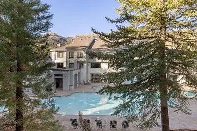 a large house with a swimming pool in the yard at Palisades Tahoe Lodge Rentals Studio #205 in Olympic Valley