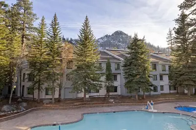 an apartment building with a swimming pool and trees at Palisades Tahoe Lodge Rentals Studio #232 in Olympic Valley