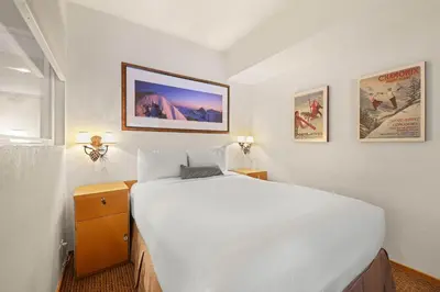 a bedroom with a large white bed and posters on the wall at Palisades Tahoe Lodge Rentals Studio #223 in Olympic Valley