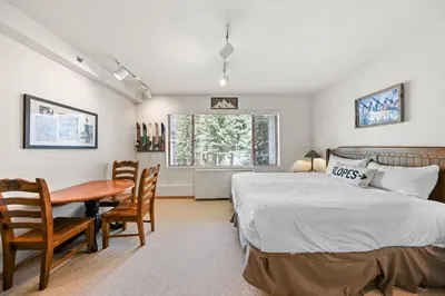 a bedroom with a bed and a desk and a table at Palisades Tahoe Lodge Rentals Studio #248 in Olympic Valley