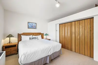 a bedroom with a large bed and a wooden closet at Palisades Tahoe Lodge Rentals Studio #248 in Olympic Valley