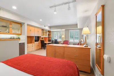 a bedroom with a red bed and a kitchen at Palisades Tahoe Lodge Rentals Studio #237 in Olympic Valley