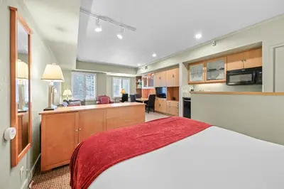 a bedroom with a large bed and a kitchen at Palisades Tahoe Lodge Rentals Studio #238 in Olympic Valley