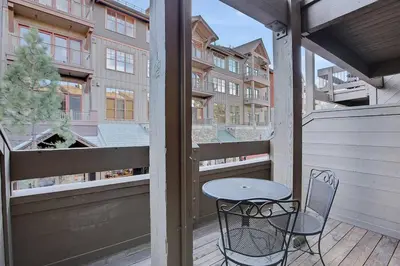 a table and chair on a balcony with a view of a building at Slope Side Studio in Northstar Village! in Truckee