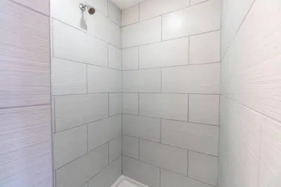 a white bathroom with a shower with white tiles at Midtown Modern - Stylish 2BR Lodging in Reno in Reno