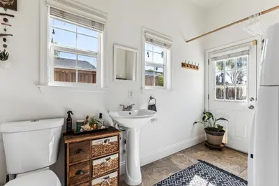 a bathroom with a sink and a toilet and two windows at ¤ Old Folsom La Boheme Artist Retreat + Jacuzzi ¤ in Folsom