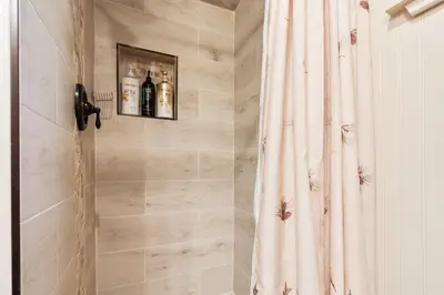 a bathroom with a shower with two bottles of wine at Lewis Creek cabin near Yosemite king beds in Oakhurst