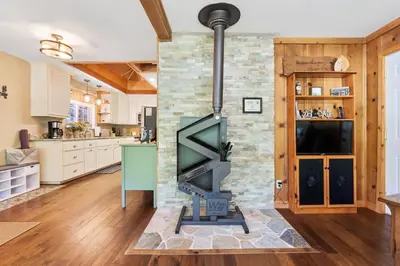 a living room with a stone fireplace in a kitchen at Lewis Creek cabin near Yosemite king beds in Oakhurst