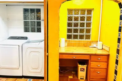 a yellow kitchen with a washing machine and a window at Beautiful Spanish-Styled Home in Fresno