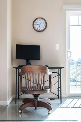 a chair and a desk with a computer and a clock at Master Suite Fraser Family Vineyard Stay in Amador in Plymouth